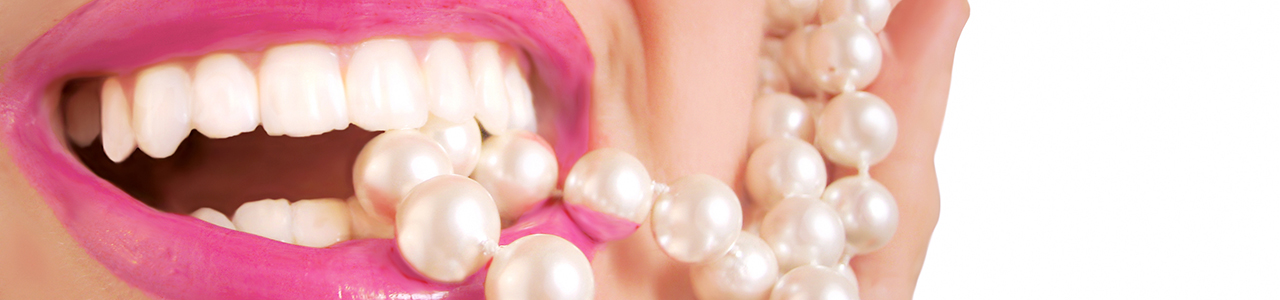 Lippen einer Frau mit pinkem Lippenstift. Zwischen ihren Zähnen beißt sie auf eine Perlenkette.