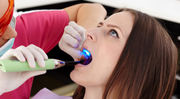 Zahnärztin macht Zahnfüllung bei Patientin.