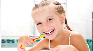 Kleines Mädchen lächelt und hält Zahnbürste