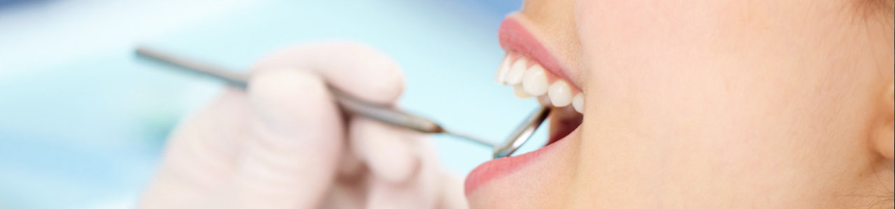 Zahnarzt untersucht Zähne einer Patientin mit Zahnarzt-Spiegel