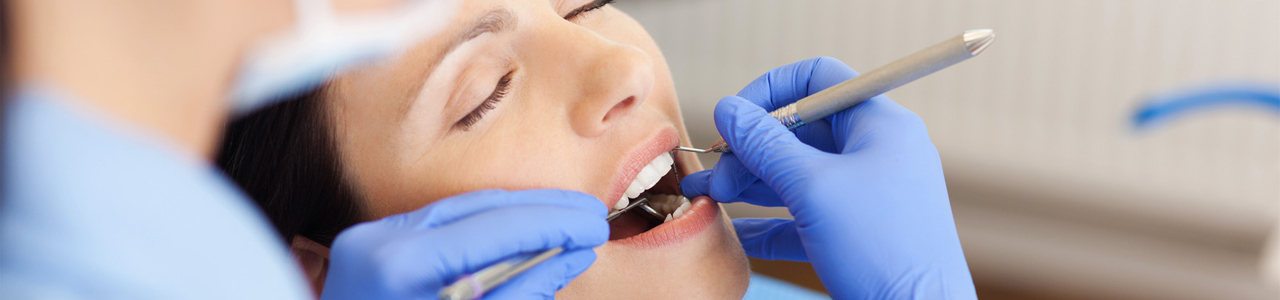 Zahnarzt untersucht Zähne einer erwachsenen Patientin