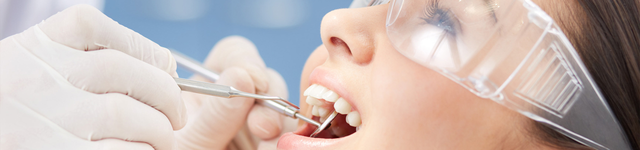 Zähne im offenen Mund einer Frau werden von einem Zahnarzt untersucht.