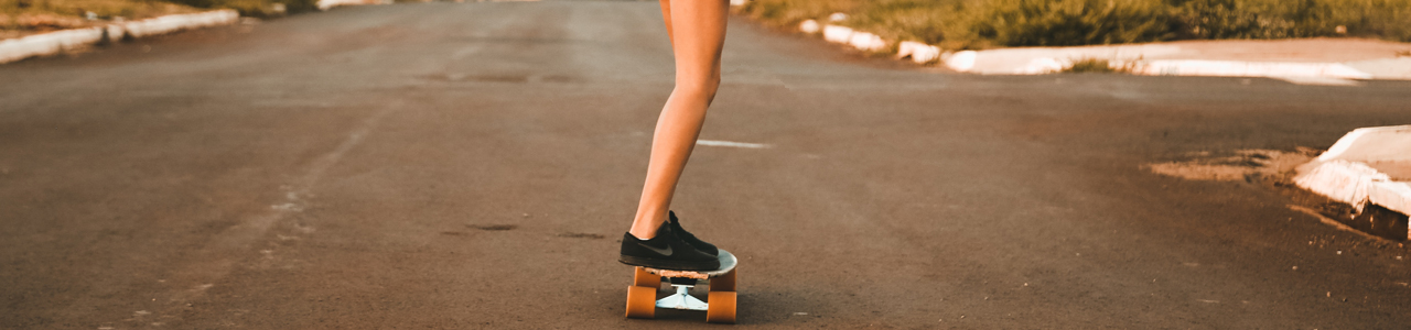 Eine junge Frau steht auf einem Skateboard auf einer Straße in einem Wohngebiet.